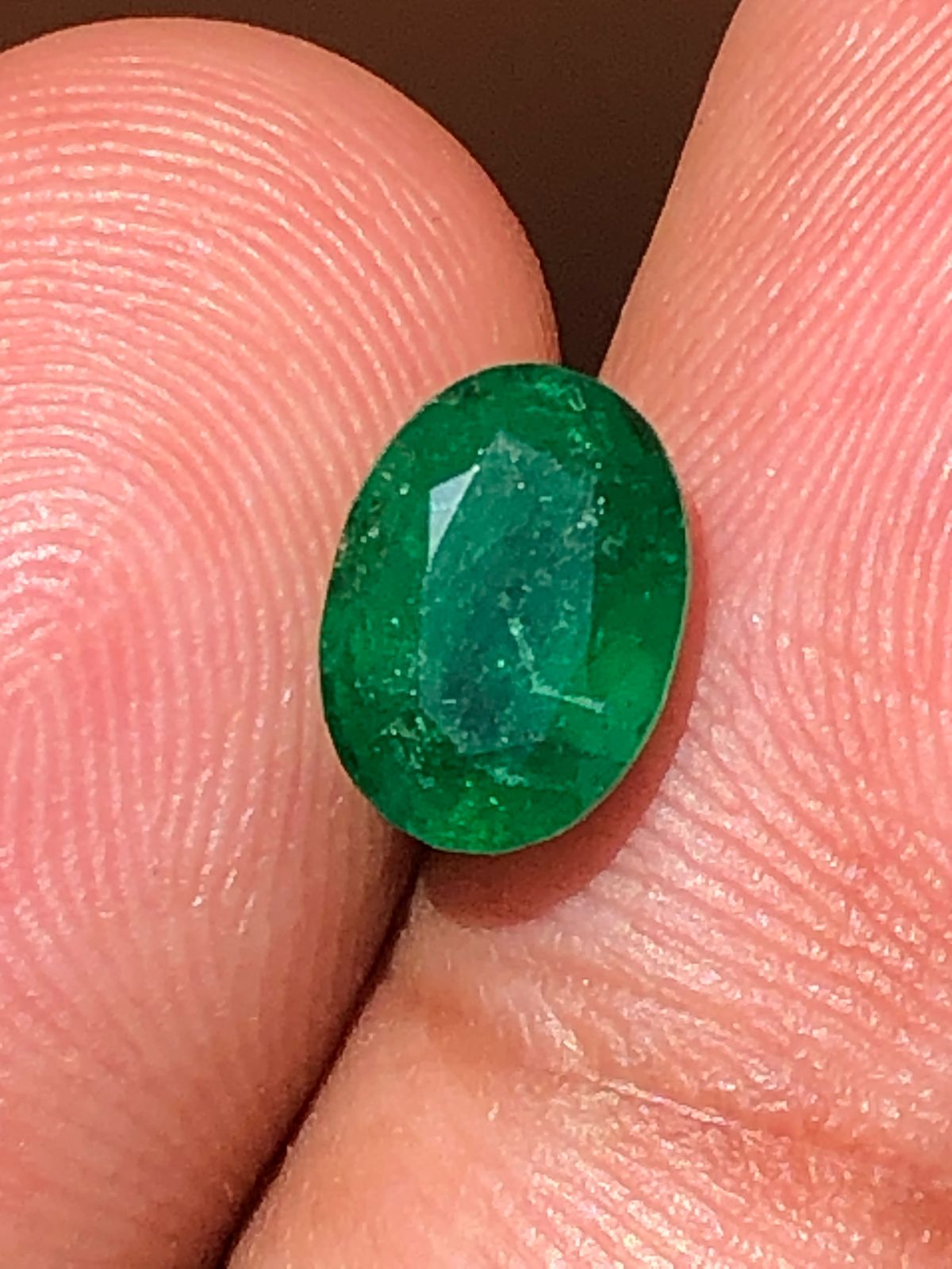 Green gemstone held between two fingers