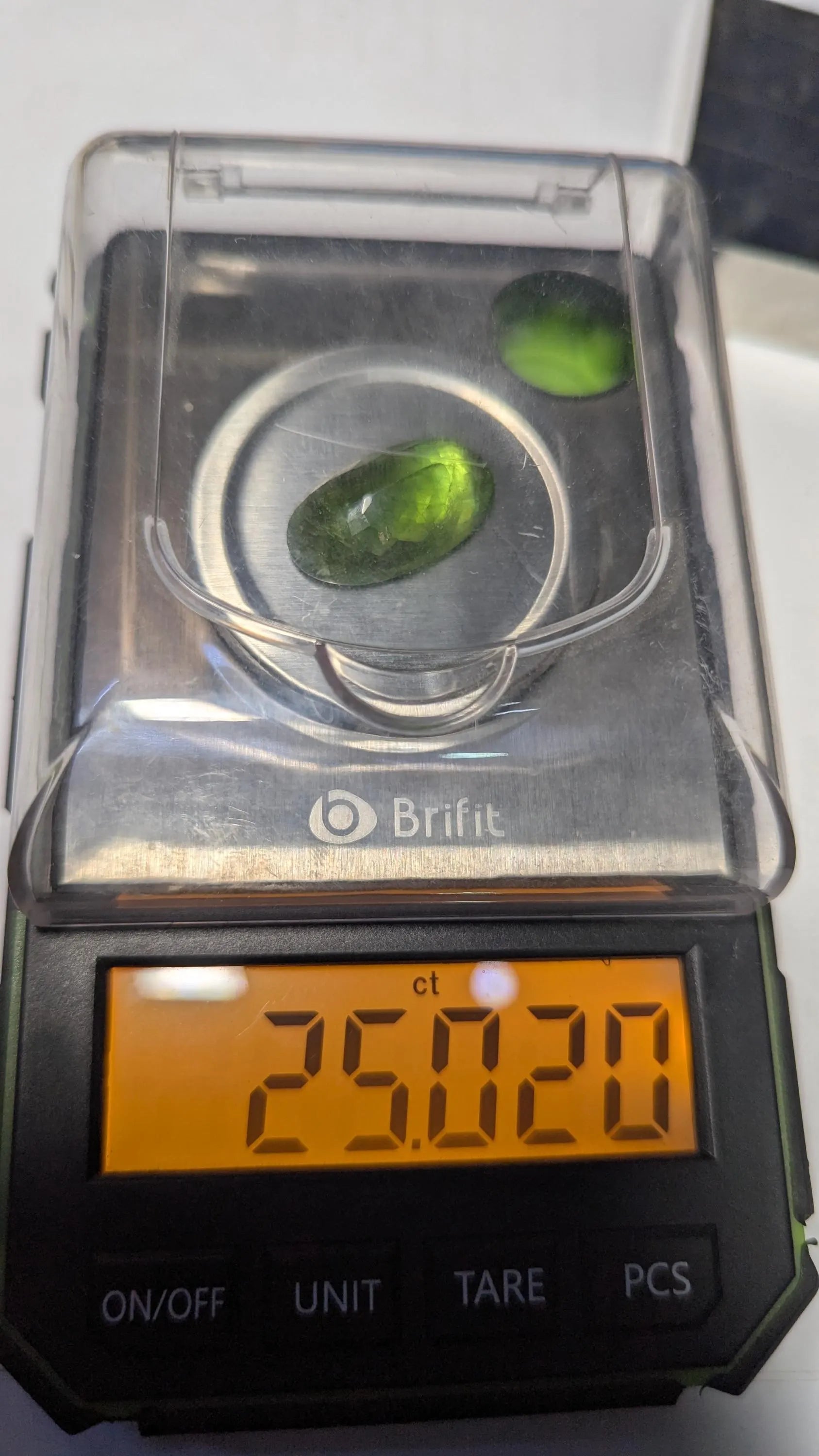 Peridot green stones on a Brift digital scale displaying a weight of 25.029 carats.