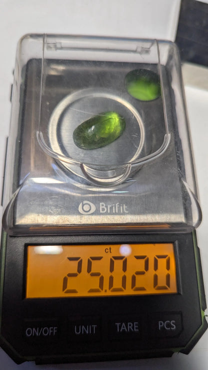 Peridot green stones on a Brift digital scale displaying a weight of 25.029 carats.